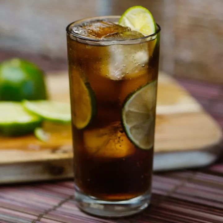 a cuba libre cocktail with cola and garnished with lime slices